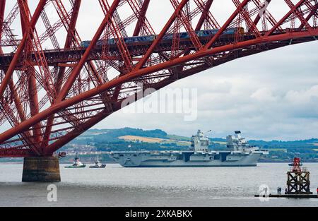 South Queensferry, Schottland, Großbritannien. Juli 2024. Die Royal Navy Flugzeugträger HMS Queen Elizabeth verlässt die Werft von Rosyth und segelt bei Ebbe unter der Forth Bridge nach Abschluss der Reparaturen. Iain Masterton/Alamy Live News Stockfoto