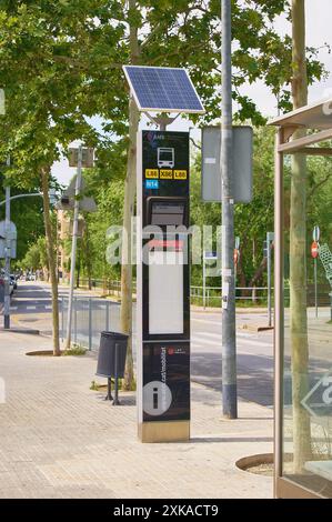 Viladecasn, SPANIEN - 22. JULI 2024: Moderne, nachhaltige Bushaltestelle mit Solarpaneelen und digitalen Streckenanzeigen auf einer von Bäumen gesäumten Stadtstraße. IT-stan Stockfoto