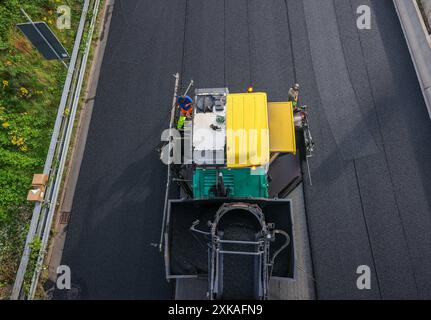 Essen, Nordrhein-Westfalen, Deutschland - Strassenbau, Asphaltfertiger und Strassenwalzen verbauen neu, offenporigen, Fluesterasphalt auf der Autobahn A52, hier zwischen den Anschlussstellen Essen-Kettwig und Essen-Ruettenscheid in Fahrtrichtung Dortmund. Essen Nordrhein-Westfalen Deutschland *** Essen, Nordrhein-Westfalen, Deutschland Straßenbau, Asphaltfertiger und Straßenwalzen legen auf der Autobahn A52, hier zwischen den Anschlussstellen Essen Kettwig und Essen Ruettenscheid in Richtung Dortmund Essen Nordrhein-Westfalen Deutschland, neuen, offenporigen, fluessigen Asphalt ab Stockfoto