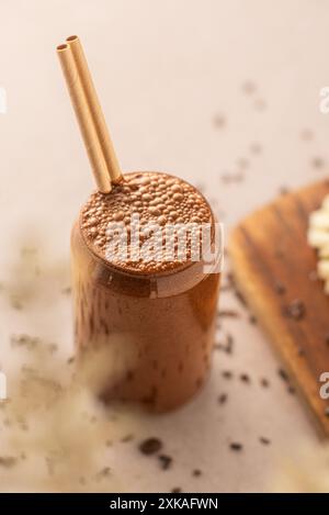 Schokoladen-Smoothie auf einem Coffee-Shop-Tisch, mit geschnittenen Bananen an der Seite. Veganer Smoothie, gesundes Getränk. Stockfoto