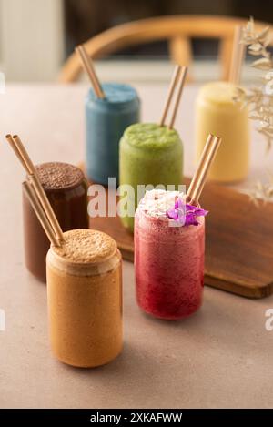 Auswahl an farbenfrohen Smoothies, wunderschön dekoriert, am Coffee Shop Tisch. Stockfoto