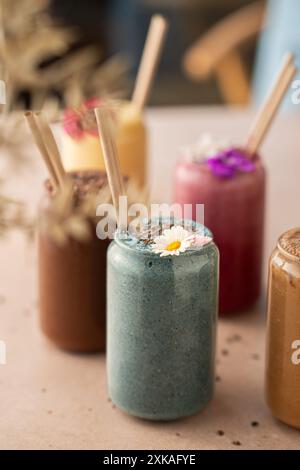 Auswahl an farbenfrohen Smoothies, wunderschön dekoriert, am Coffee Shop Tisch. Stockfoto