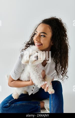 Frau entspannt sich auf dem Stuhl mit ihrem weißen Hund in der Hand. Stockfoto