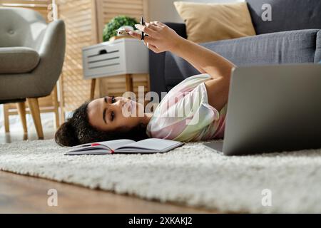 Eine Frau entspannt sich auf dem Boden, vertieft in ihren Laptop. Stockfoto
