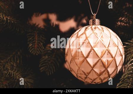 Weiße Weihnachtskugel mit goldenem Glitzer hängt an einer Tanne. Platz für Text. Stockfoto