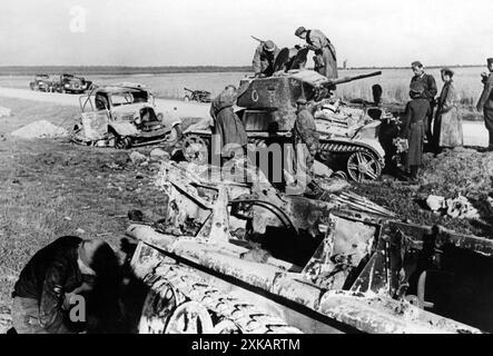 Deutsche Soldaten inspizieren einen zerstörten russischen BT-Panzer auf einer Straße an der Ostfront. [Automatisierte Übersetzung] Stockfoto