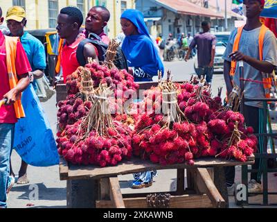 Sansibar, Tansania - Februar 2021: Viele rote Litschis werden direkt von einem Holzkarren in der Straße Afrikas verkauft. Andere berühmte Namen: Lychee, longan, Stockfoto