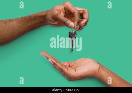 Schwarzer Mann, der den Schlüssel an die Hand der Person übergibt Stockfoto