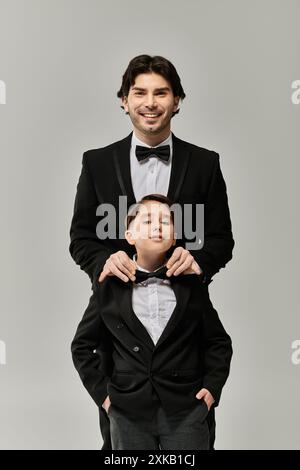 Ein Vater und ein Sohn in formeller Kleidung, der Vater passt die Fliege der Söhne an. Stockfoto