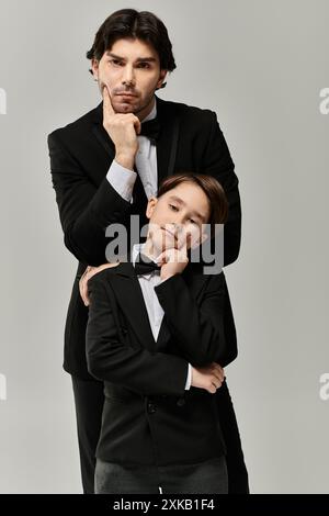 Vater und Sohn in passenden Anzügen, die nachdenklich in die Ferne blicken. Stockfoto
