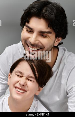 Vater und Sohn teilen einen freudigen Moment, beide lachen von Herzen. Stockfoto