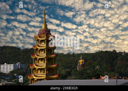 Der Gipfel der Pagode des Wat Tham Suea, umgeben von Bäumen und weißen Wolken, befindet sich in der Provinz Kanchanaburi, einem beliebten religiösen Touristenziel in Stockfoto