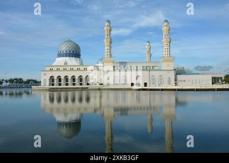 Ein atemberaubender Blick auf die Stadtmoschee in Kota Kinabalu, Malaysia, mit ihrer Reflexion auf dem ruhigen Wasser unter einem klaren blauen Himmel. Stockfoto