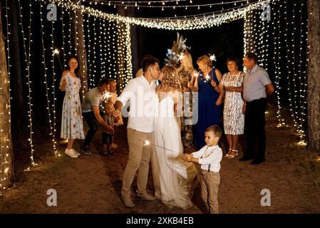 Sparkler bei der Hochzeit der Frischvermählten in den Händen fröhlicher Gäste Stockfoto