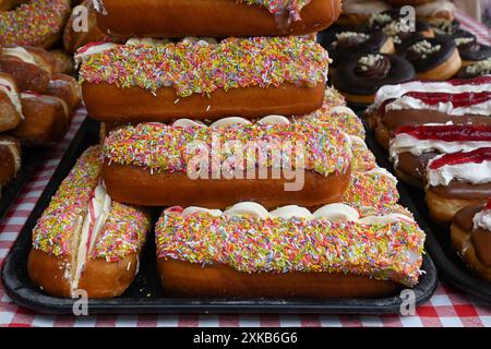 Ein Haufen langer, mit Sahne gefüllter Brötchen mit einem Haufen von Hunderten und Tausenden drauf. Stockfoto