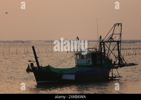 Ein lokales Fischerboot liegt am Meer und im Hintergrund nach Sonnenuntergang in der Gegend der Muschelfarm ​​a in der Provinz Chonburi in Thailand. Stockfoto