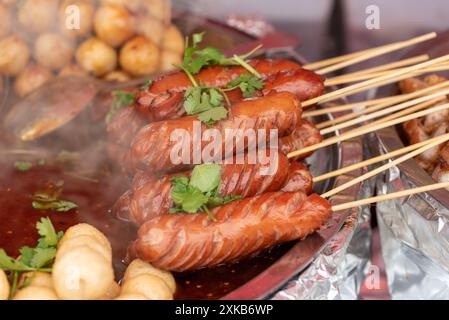 Thai Street Food, Würstchen auf Sticks mit Fleisch- und Fischbällchen in einer scharfen Brühe. Stockfoto