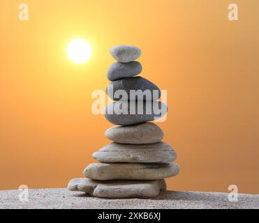 Gestapelte Steine in Pyramidenform auf einem Hintergrund bei Sonnenaufgang und Kopierraum für Design in Ihrer Arbeit, Reise oder Zen-Thema. Stockfoto