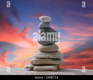 Gestapelte Steine in Pyramidenform auf einem Hintergrund bei Sonnenuntergang und Kopierraum für Design in Ihrer Arbeit, Reise oder Zen-Thema. Stockfoto