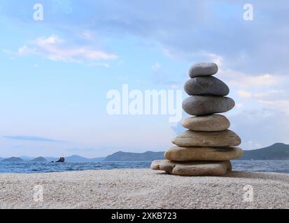 Sandsteine werden zu einer Pyramide auf See- und Wolkenhintergrund gestapelt und kopieren Platz für Design in Ihrem Work Travel oder Zen Konzept. Stockfoto