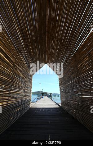 Ein Tunnel aus Bambus befindet sich auf einer Brücke, die sich an klaren Tagen in einem Resort in der Bucht von Samae San ins Meer erstreckt. Stockfoto