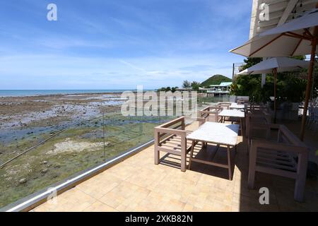 Ein Tisch zum Essen in einem Restaurant an der trockenen Küste mit Blick auf Sand, Felsen und Himmel an einem klaren Tag in Samae San Bay, Provinz Chonburi, Thaila Stockfoto