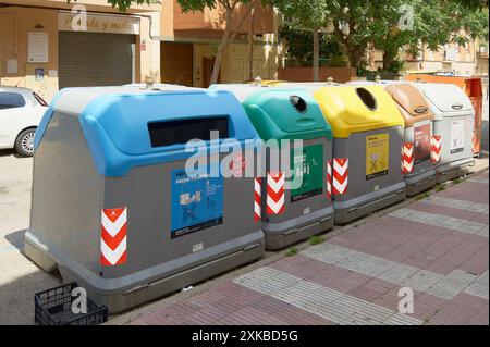 Viladecasn, SPANIEN - 22. JULI 2024: Eine Reihe farbenfroher Recyclingbehälter in einer städtischen Umgebung, die jeweils für verschiedene Abfallarten bestimmt sind. Stockfoto