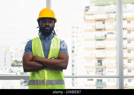 Porträt eines afrikanischen Arbeiters in der Bau- und Instandhaltungsindustrie, er steht mit überkreuzten Armen in die Kamera, er trägt Schal, Safe Stockfoto