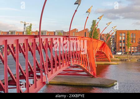 Amsterdam, Niederlande - 17. Mai 2018: Rote Python-Brücke Pythonbrug über den Wasserkanal in der Hauptstadt Ost in der Abenddämmerung. Stockfoto