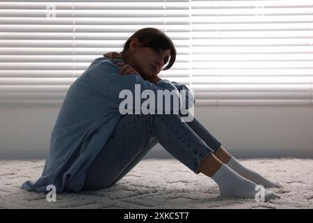 Einsamkeitskonzept. Traurige Frau, die zu Hause auf dem Boden sitzt Stockfoto