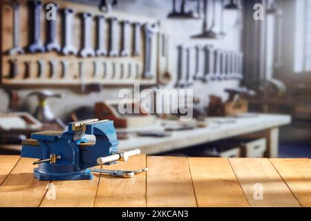 Schlosserschrauber auf Holzarbeitstisch in der Handwerkstatt. Unscharfe Wand mit Werkzeugen im Hintergrund. Stockfoto