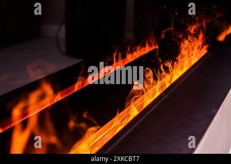 Nahaufnahme realistischer Flammen in einem modernen elektrischen Kamin. Das Bild unterstreicht die Wärme und das gemütliche Ambiente, das durch den elektrischen Kamin erzeugt wird. Stockfoto