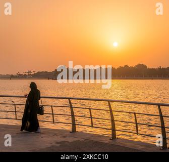 Die Paranja bedeckte muslimische Frau an der Jeddah Corniche (Uferpromenade) in Saudi-Arabien und beobachtete den wunderschönen Sonnenuntergang im Nahen Osten. Stockfoto