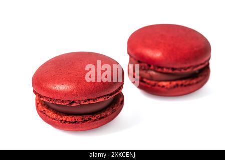 Zwei rote Macarons mit Erdbeerfüllung werden in einer Nahaufnahme dargestellt. Der Macaron ist auf einem weißen Hintergrund isoliert, was seine Lebendigkeit unterstreicht Stockfoto