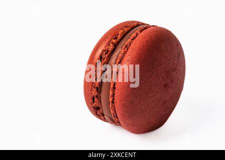 Ein einzelner, roter Macaron mit Erdbeerfüllung wird in einer Nahaufnahme dargestellt. Der Macaron ist auf einem weißen Hintergrund isoliert, was seine vibra hervorhebt Stockfoto