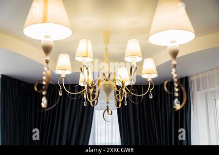 Eleganter Kronleuchter mit mehreren Lampen in einem modernen Speisesaal mit dunkelblauem Vorhang. Stockfoto