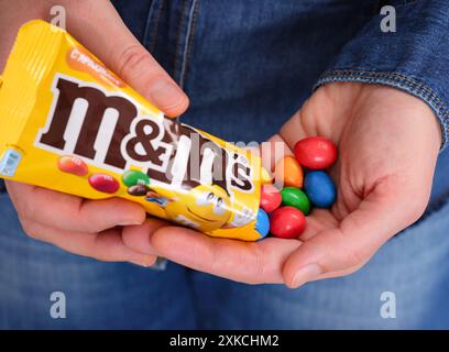 Tambow, Russische Föderation - 23. Januar 2024 Frau, die M&Ms Bonbons aus dem Rudel in die Hand gießt. Stockfoto