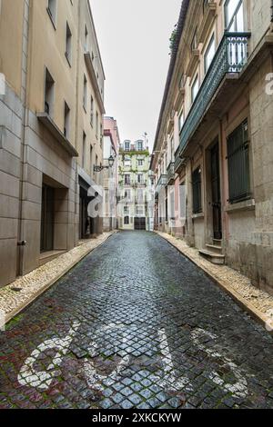Kopfsteinpflasterstraße mit Stoppschild und einer Mischung aus neuen und baufälligen Gebäuden im Zentrum von Lissabon in Portugal Stockfoto