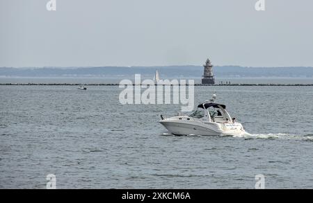 Stamford, CT - 23. Juni 2024: Boot im Hafen mit Stamford Harbor Ledge Lighthouse im Hintergrund. Stockfoto