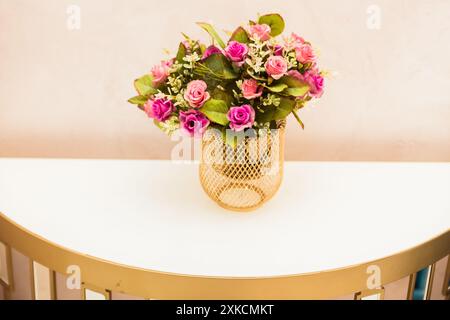 Nahaufnahme eines künstlichen Blumenarrangements in einer Goldvase. Stockfoto