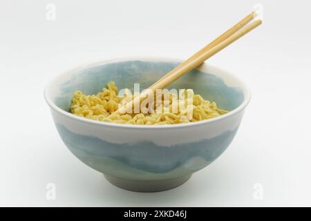 Instant-Nudeln in einer Schüssel mit Stäbchen auf weißem Hintergrund Stockfoto