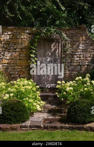 Alte hölzerne Tür in Steinmauer im englischen Landgarten, england Stockfoto