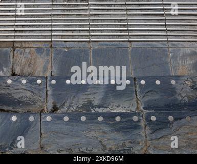 Erhöhte Metallstreifen und -Kreise als rutschfeste Absturzsicherung auf Gehsteig in Cardiff Bay. Vom Juli 2024. Stockfoto