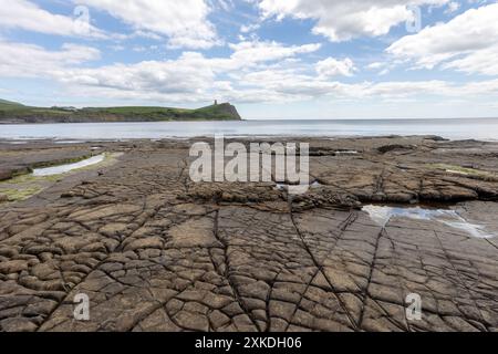 Meerblick vom Strand Kimmeridge Bay aus. Es werden verschiedene Felsformationen gezeigt. Es gibt einen blauen Himmel mit minimaler Wolkenbedeckung. Stockfoto