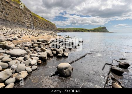 Meerblick vom Strand Kimmeridge Bay aus. Es werden verschiedene Felsformationen gezeigt. Es gibt einen blauen Himmel mit minimaler Wolkenbedeckung. Stockfoto