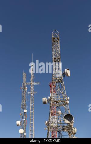 Drei hohe Telekommunikationstürme mit Antennen oben. Der Himmel ist blau und klar. Stockfoto