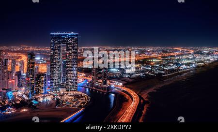 Ein Blick aus der Vogelperspektive auf Dubais Skyline bei Nacht mit beleuchteten Wolkenkratzern und einer Autobahn, die sich in die Ferne erstreckt. Stockfoto