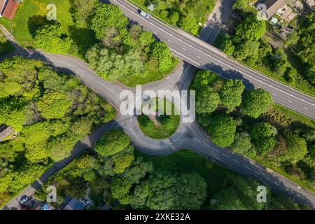 Blick von oben nach unten auf einen kleinen Kreisverkehr, der im Sommer von üppigem Grün umgeben ist Stockfoto