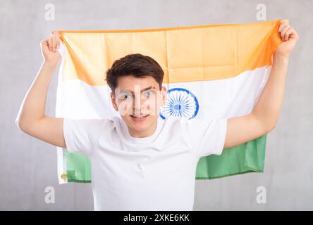 Glücklicher junger Mann mit der Flagge Indiens vor eingefärbtem Hintergrund Stockfoto
