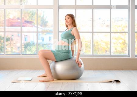 Sportliche junge schwangere Frau, die zu Hause auf dem Fitball trainiert Stockfoto